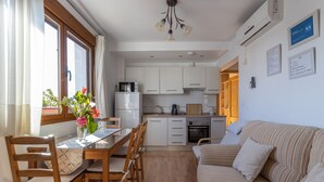 Un espai habitable compacte amb zona de menjador, petita cuina i sofà.