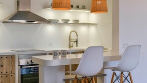 Una cocina moderna con horno Bosch, armarios blancos y dos lámparas colgantes naranjas.