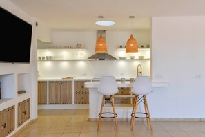 Une cuisine moderne dotée d’un îlot central, de deux suspensions et de meubles en bois.