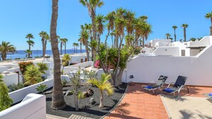 Un jardín en la azotea con palmeras, una piscina y sillones de descanso.