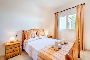 A bedroom with a bed, bedside tables, a lamp, and a window with curtains.