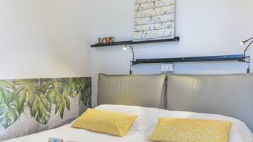 Una cama con dos almohadas, una pared con una ilustración de pájaro y una estantería con un letrero que dice 'LOVE'.