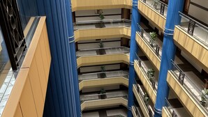 Un atrium à plusieurs niveaux, doté d’un espace central ouvert, entouré de balcons agrémentés de rampes et de plantes en pot.