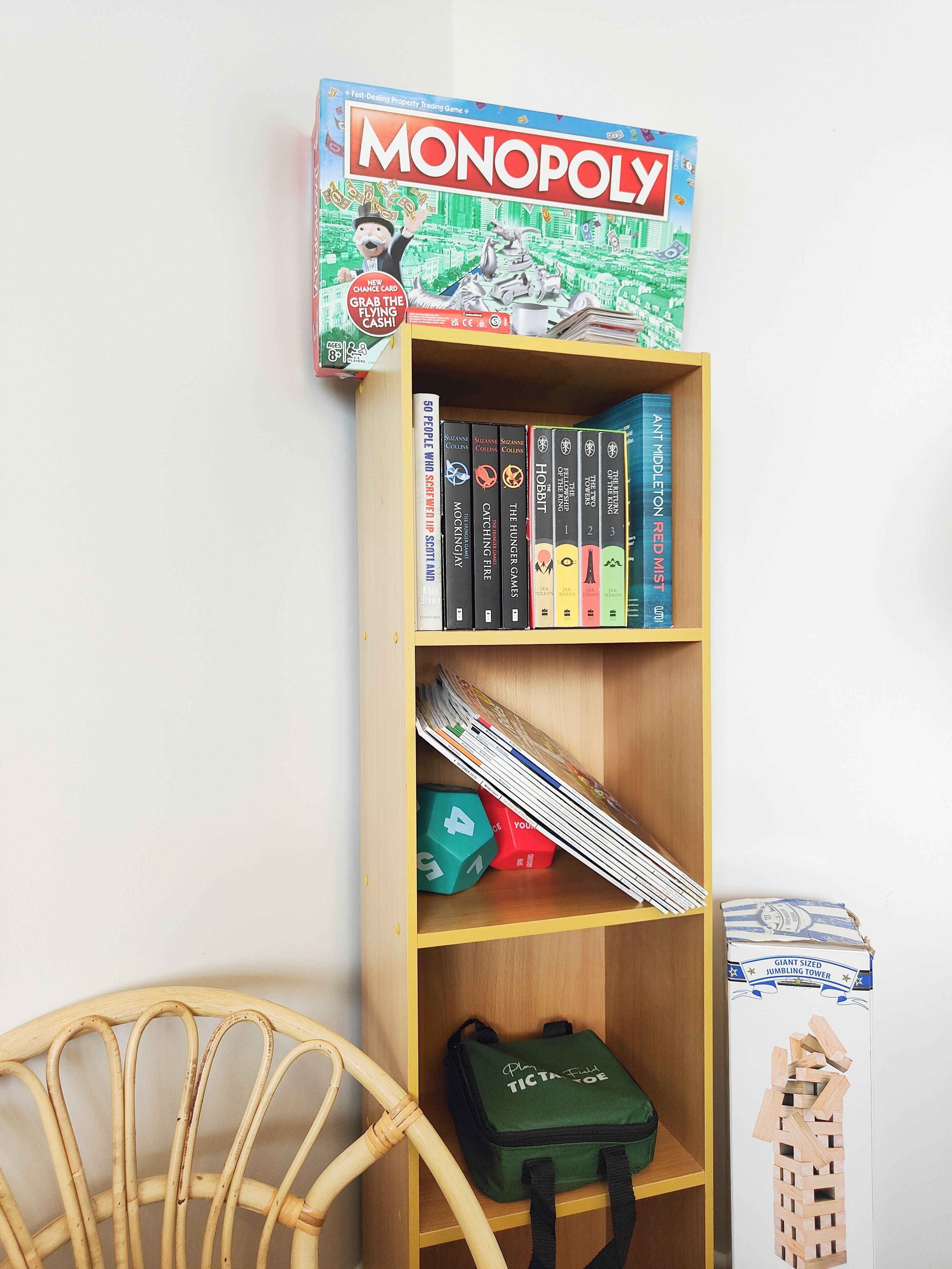 Ein Bücherregal mit Monopoly, Büchern und einer Ticta Tuff Tasche.