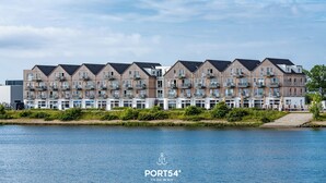 Una hilera de edificios modernos de varios pisos con balcones, junto a una masa de agua.