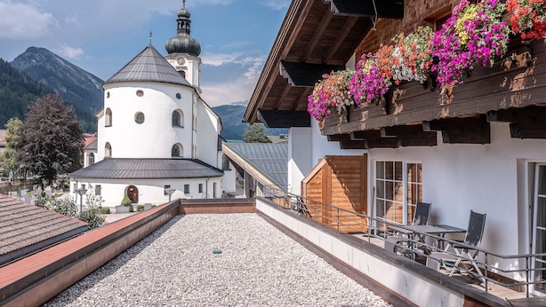 Ein Gebäude mit weißer Fassade, einem Glockenturm und einem Balkon mit bunten Blumen.