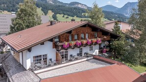 Ein Chalet mit einem geneigten Dach, einem Balkon mit Blumenkästen und Blick auf die Berge.