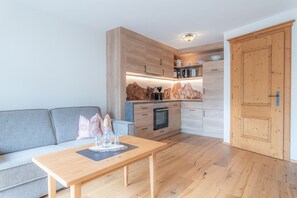 A compact kitchen with wooden cabinets, a built-in oven, and a coffee machine.
