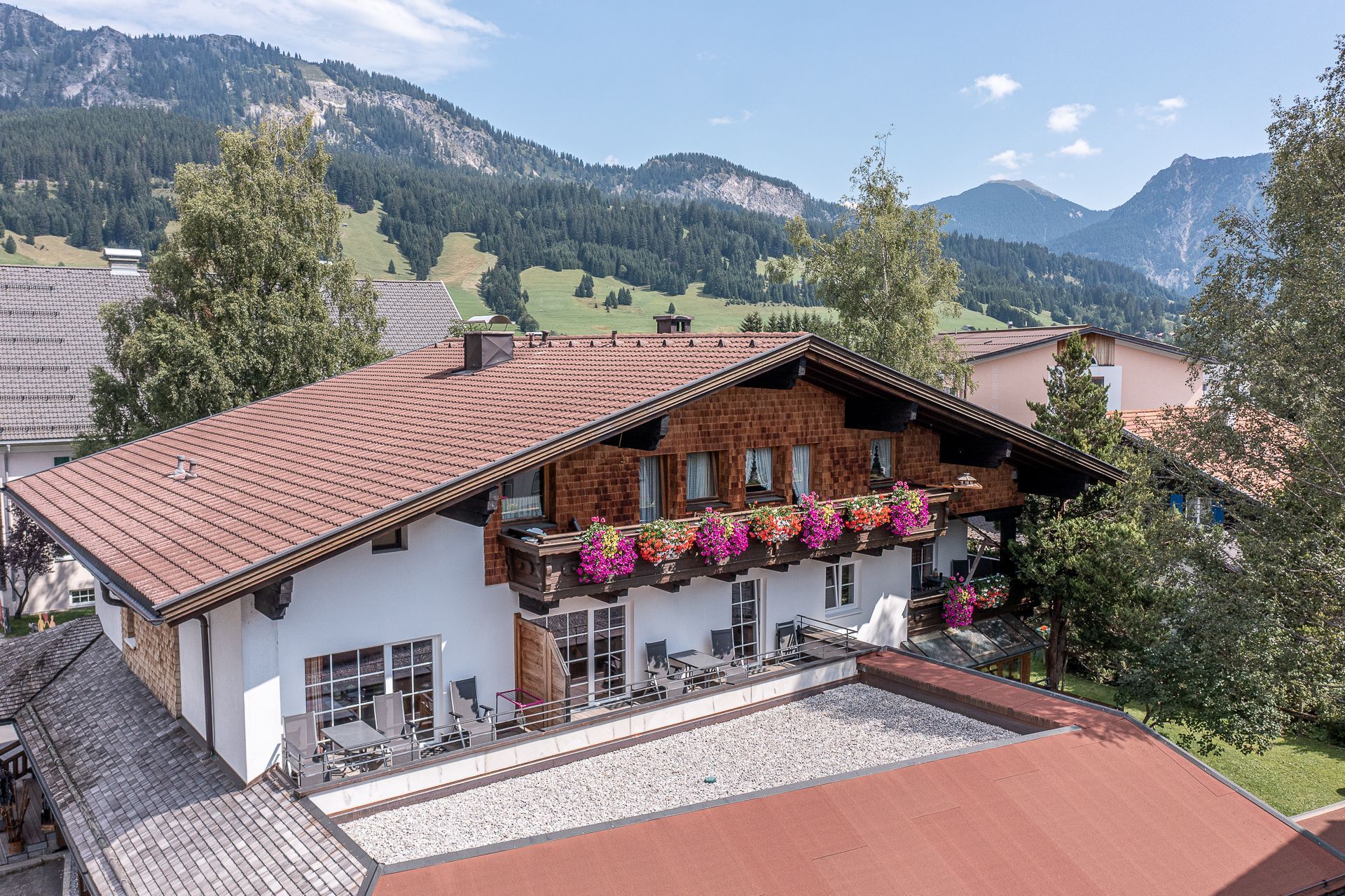 A chalet with a sloped roof, a balcony with flower boxes, and a view of mountains.