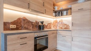 Eine moderne Küche mit Holzausbau, einem eingebauten Backofen und einer Spritzschutzwand mit Bergmotiv.