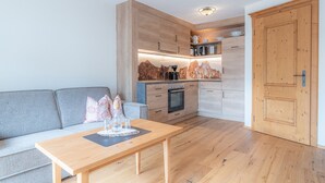 Eine kleine Küche mit Holzausstattung, einem Einbauofen und einer Kaffeemaschine.