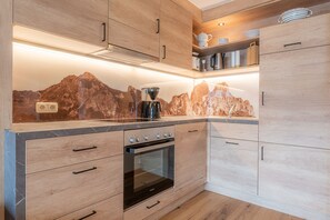A modern kitchen with wooden cabinets, a built-in oven, and a backsplash with a mountain design.
