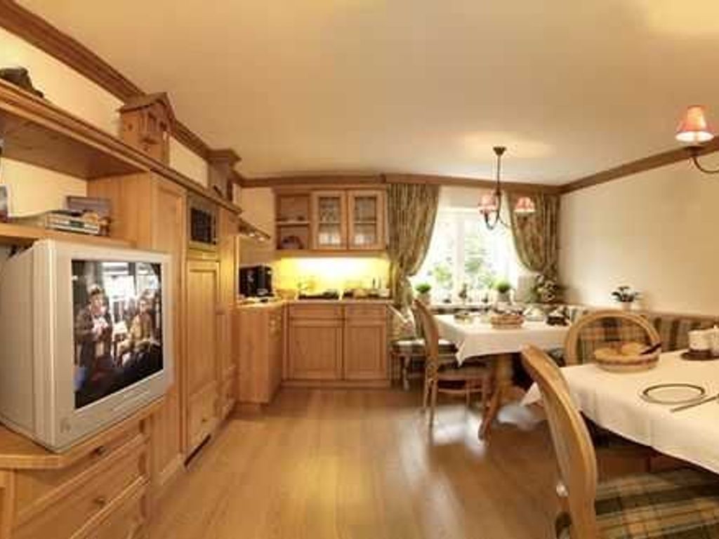 Een gezellige keuken met houten kastjes, een eettafel en een televisie.