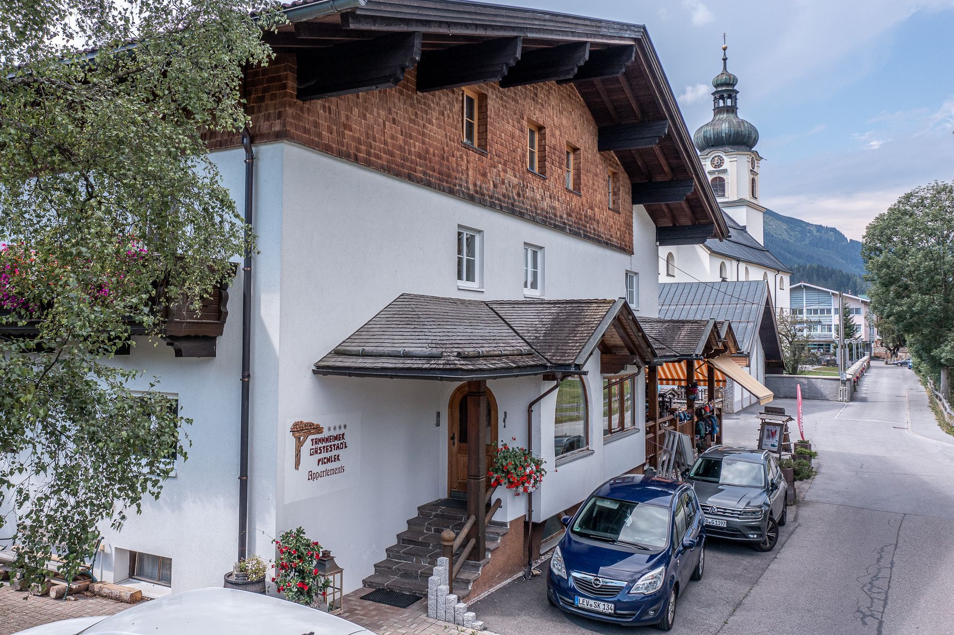 Un bâtiment traditionnel à la façade blanche, doté de balcons en bois et d’un clocher.