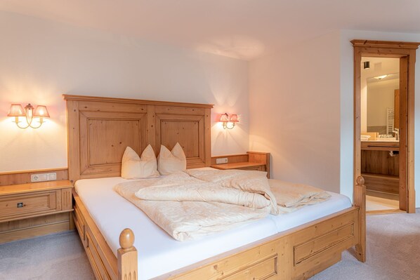 A bedroom with a wooden bed, bedside tables, and wall-mounted lamps.