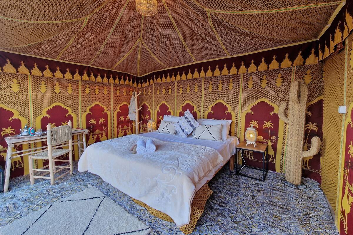 A room with a bed, a table, chairs, and a decorative ceiling.