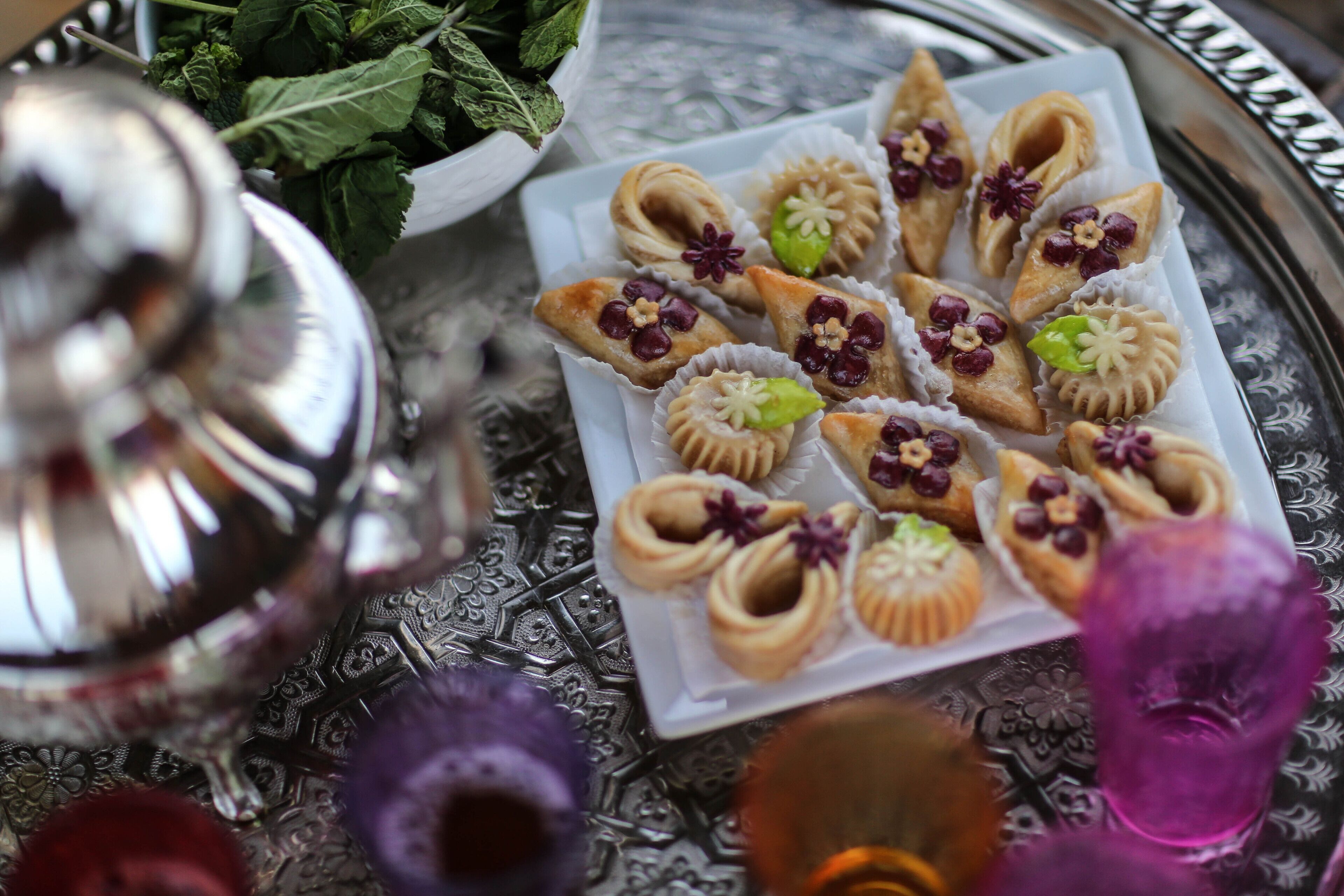 A safata de pastissos amb detalls decoratius, una teiera platejada i un mantell amb dibuixos.