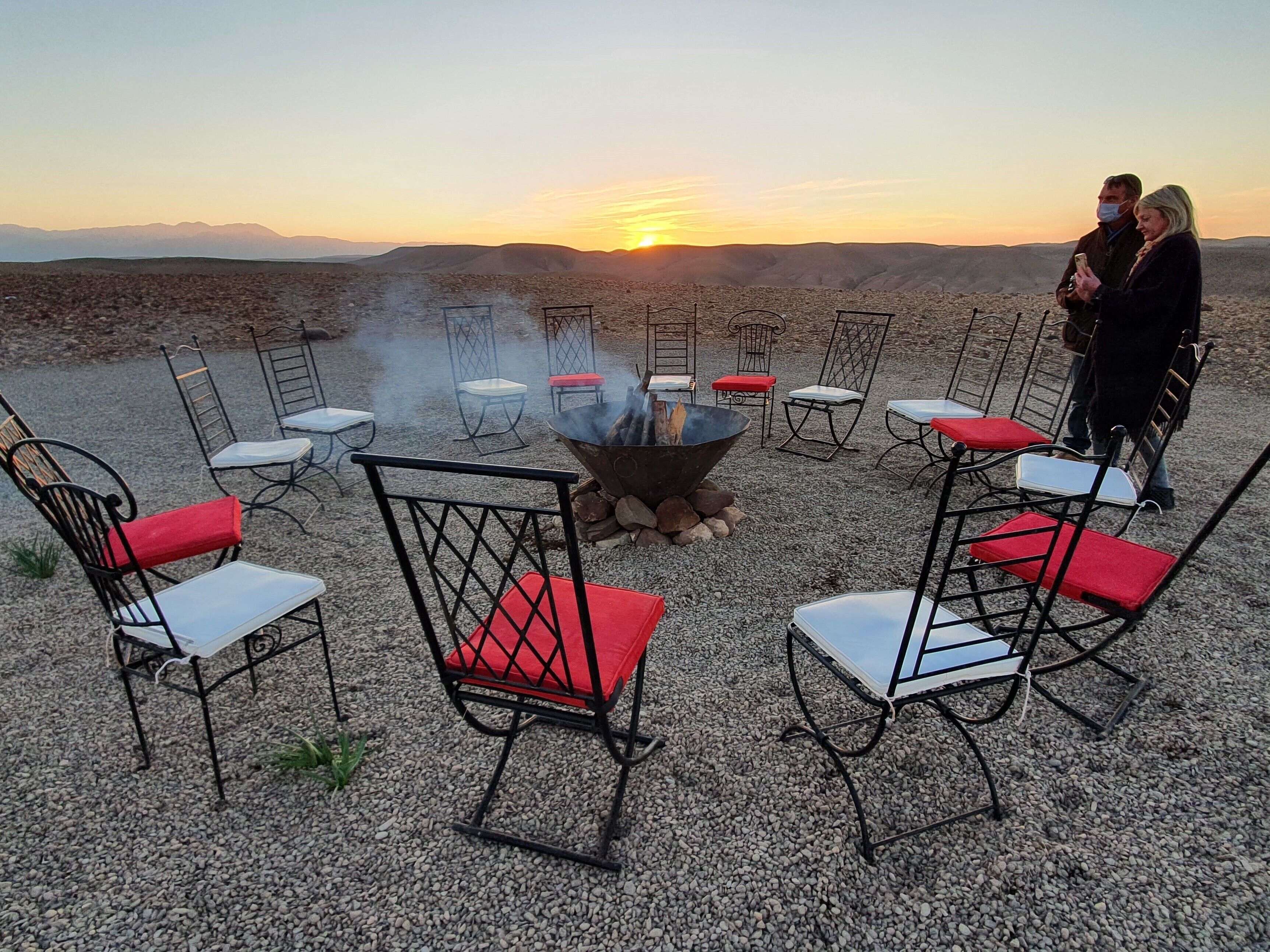 An outdoor seating area with metal chairs and a central fire pit.