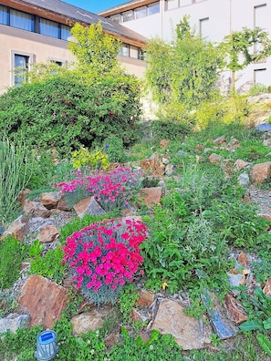 A landscaped garden with rocks, shrubs, and pink flowers. - Terres de France - Le Domaine du Palais (Saint-Lizier)