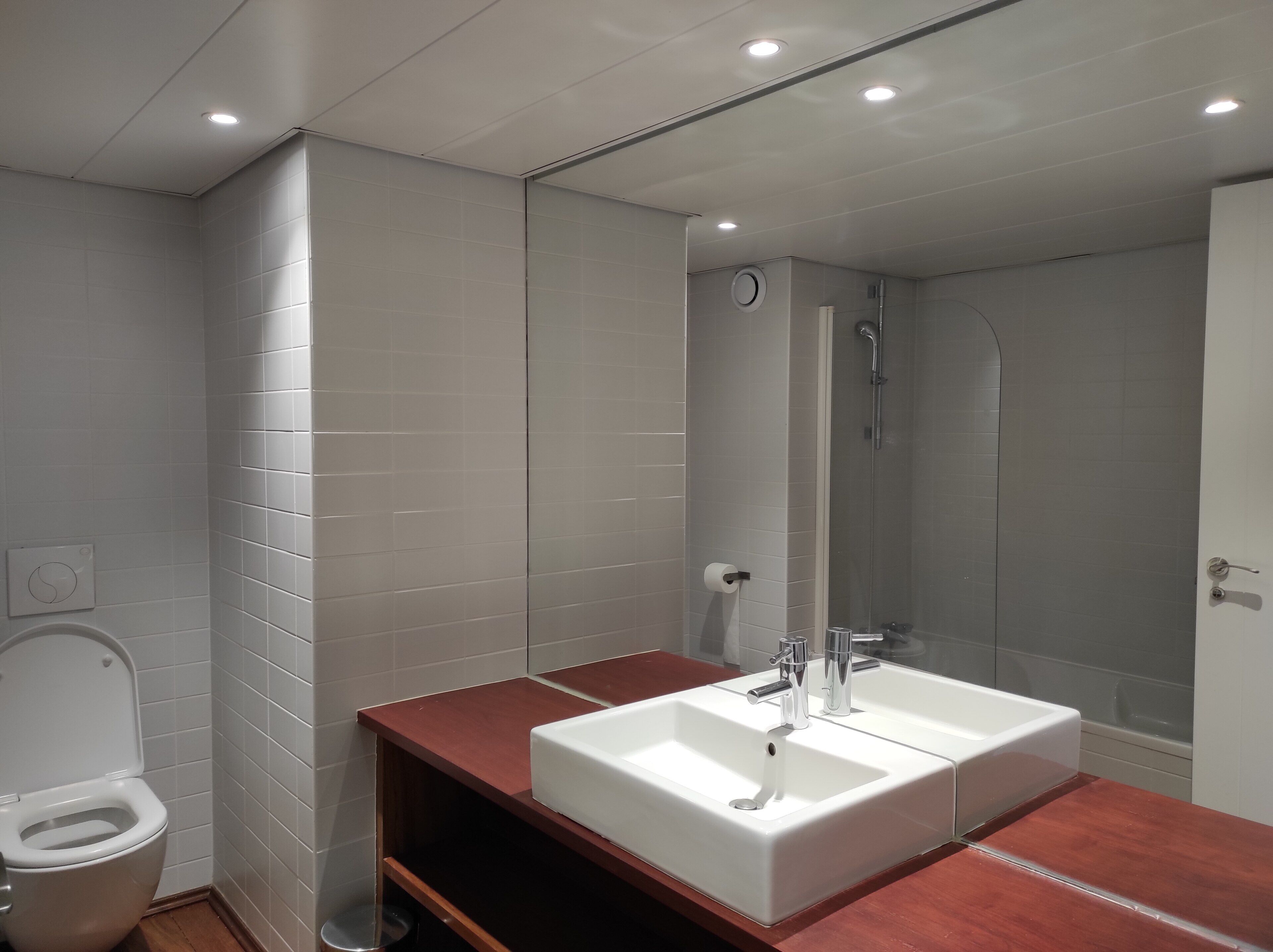 A modern bathroom with a white sink, a toilet, and a glass-enclosed shower.