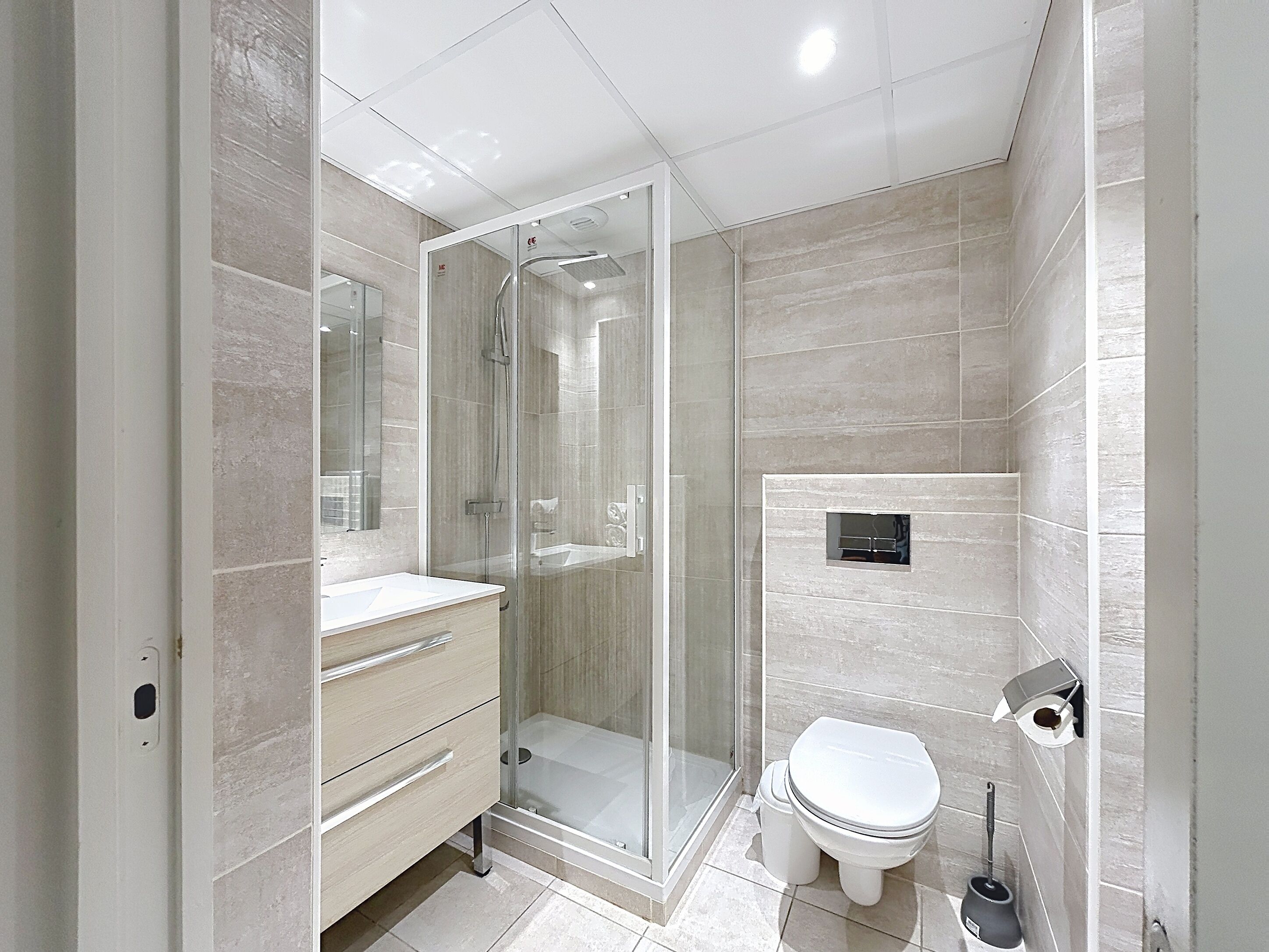 A modern bathroom with a glass-enclosed shower, a toilet, and a vanity with drawers.