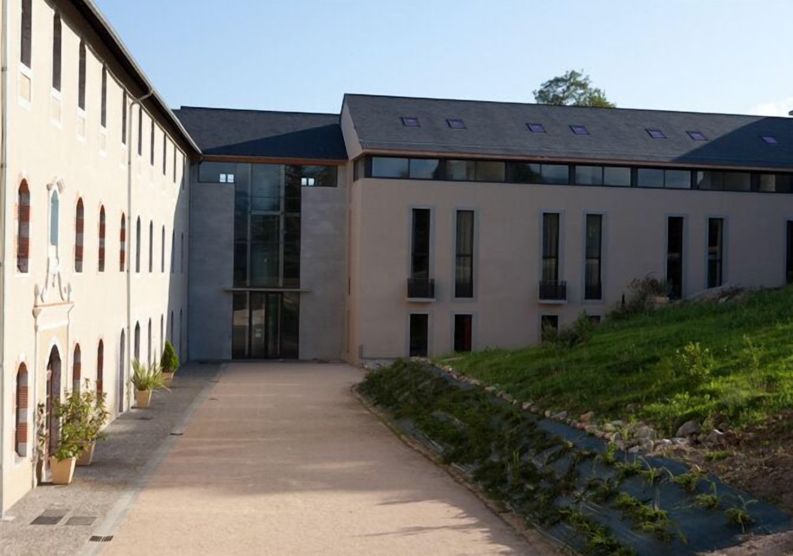 A building with a modern architectural style, featuring a central glass entrance and a symmetrical facade with multiple windows.