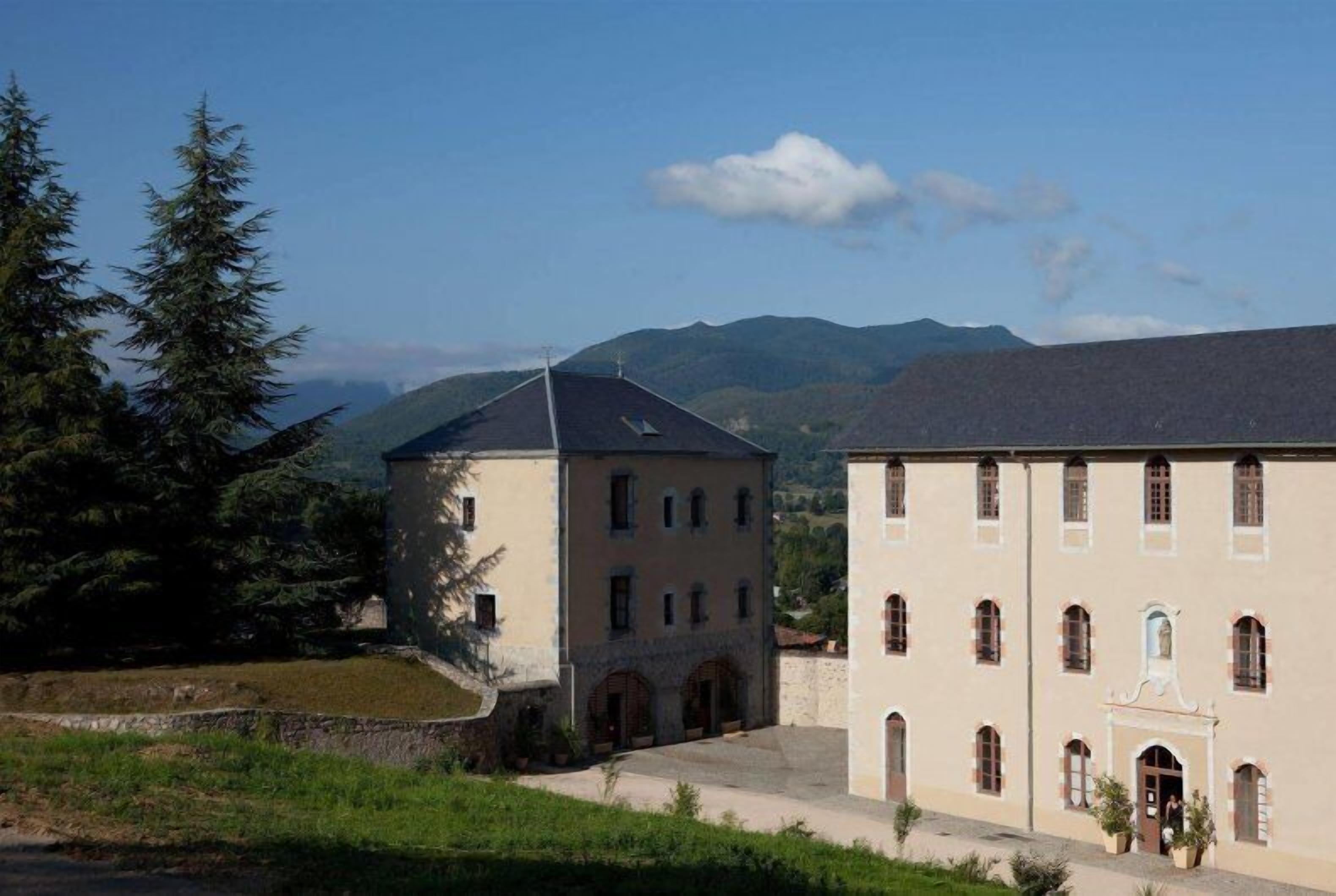 A building with a courtyard, surrounded by trees and mountains.