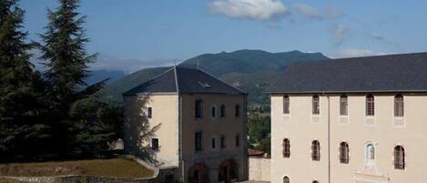 A building with a courtyard, surrounded by trees and mountains.