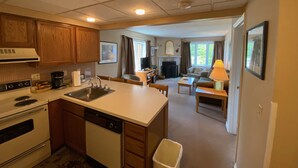 A compact kitchen with a dishwasher, stove, and a dining area with a table and chairs.
