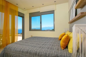 A bedroom with a bed, a window with a view, and a curtain.