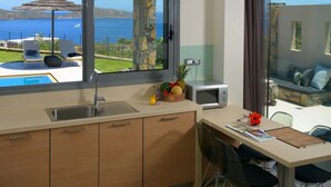 Een moderne keuken met uitzicht op zee, een zwembad en een eethoek met een tafel en stoelen.