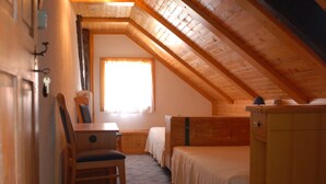 A cozy attic bedroom with a sloped ceiling, a wooden desk, a chair, a bed, and a dresser. - Paradise for hikers. Family friendly. (Crni Vrh nad Idrijo)
