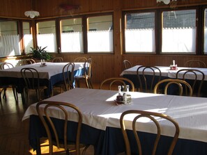 A restaurant with multiple tables, each with a white tablecloth and blue chair skirts.