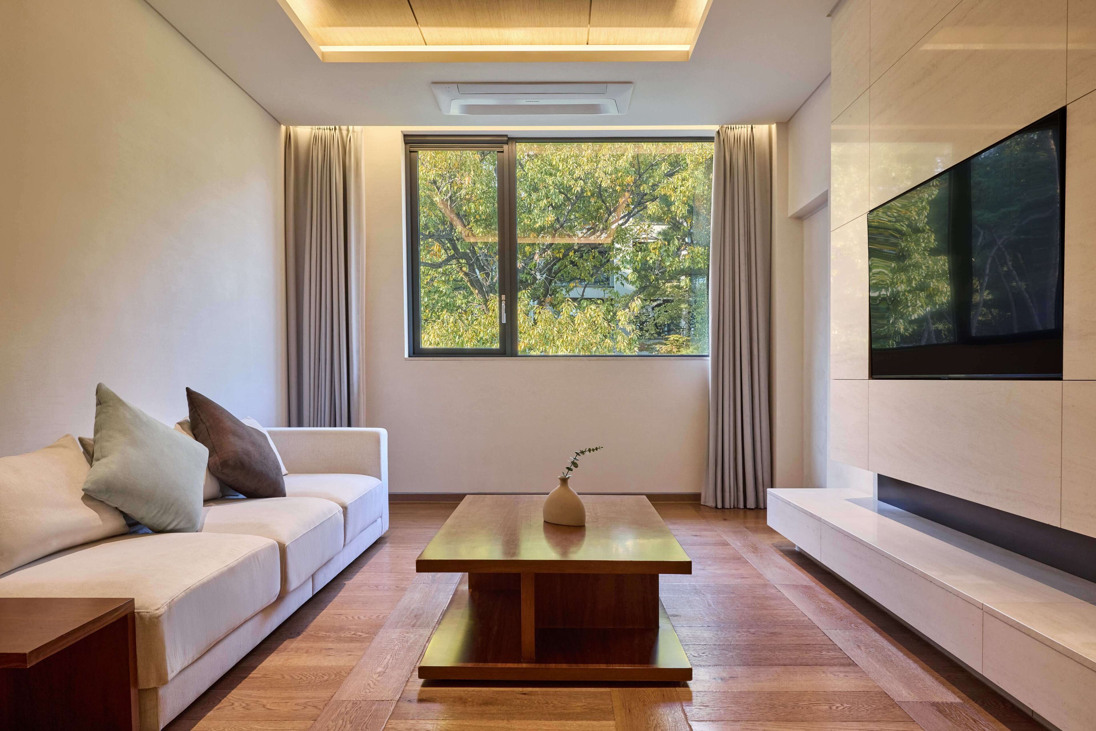 Una sala de estar moderna con un sofá, una mesita de centro y un ventanal con cortinas.