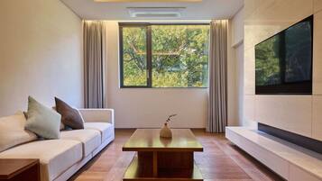 Una sala de estar moderna con un sofá, una mesita de centro y un ventanal con cortinas.
