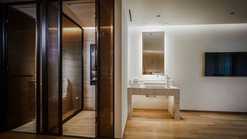Une salle de bain moderne avec une porte en verre, un lavabo en marbre et un grand miroir.