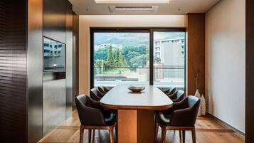 A modern conference room with a large table and chairs, large windows with a view of buildings and greenery.