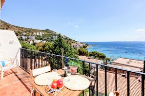 A balcony with a table set for two, overlooking a coastal town and the sea. - STA BARBARA 27 Roses (Rosas / Roses)