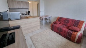 A compact living space with a kitchenette, a sofa, and a dining table.