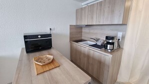 A compact kitchen with a microwave, coffee maker, and a sink.