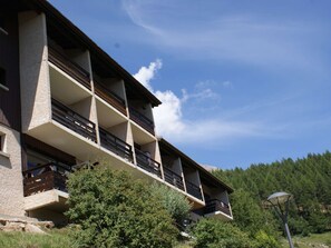 A multi-story building with balconies, surrounded by trees and a clear sky. - Charming Renovated Studio 4 Pers, South Balcony, Near Station (Saint-Michel-de-Chaillol)