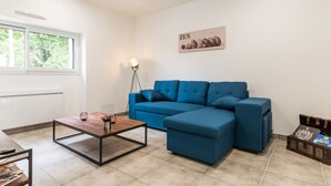 A modern living room with a blue sectional sofa, a wooden coffee table, and a floor lamp.