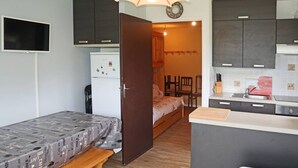 A compact room with a bed, a small kitchenette, a dining area, and a TV.