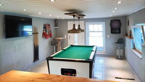 A pool table in a room with a ceiling fan, a dartboard, and a television. - Vacation apartment/holiday home for up to 5 people (children under 6 free of charge) (Clausthal-Zellerfeld)
