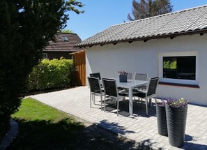 Enjoy al fresco dining on the patio surrounded by lush greenery and a beautifully tiled roof.