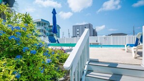 Área ao lado da piscina com um deck de madeira, piscina e cerca branca.