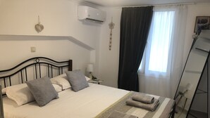 Een net opgemaakt bed met kussens, een bedlampje en opgevouwen handdoeken.