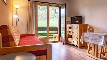A cozy room with a wooden bed, a table, a television, and a sliding glass door leading to an outdoor area.