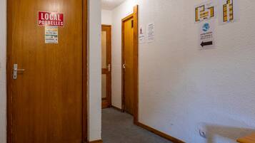 Un corridoio con porte in legno, pavimento tappezzato e indicazioni per servizi locali e indicazioni stradali.