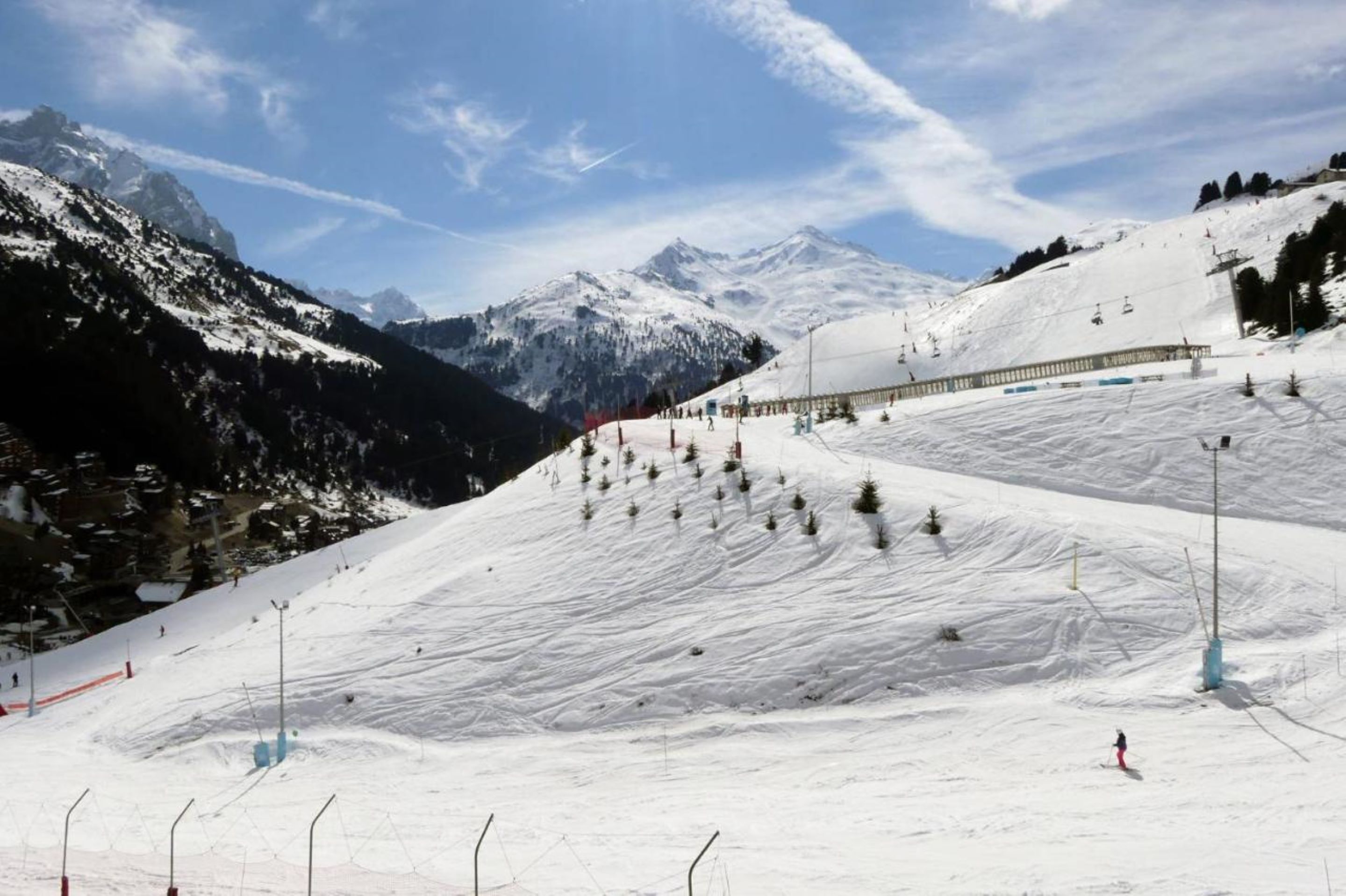 A snowy ski slope with a ski lift and a mountain backdrop.